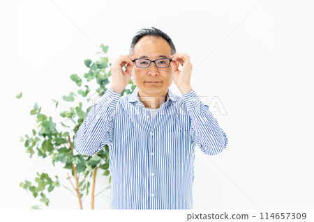Middle-aged man choosing glasses Middle-aged man choosing glasses 114657309