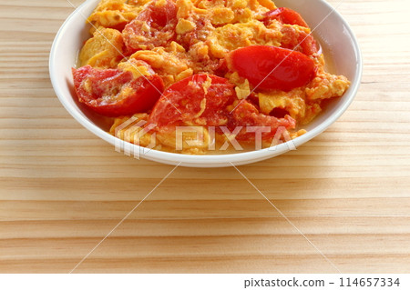 Fried eggs with tomatoes on table background 114657334