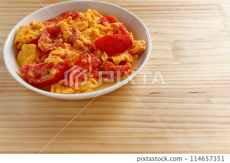 Fried eggs with tomatoes on table background Fried eggs with tomatoes on table background 114657351