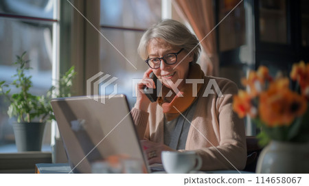 Business woman talking on the phone while working in a cafe, senior woman looking at laptop monitor, senior employment Business woman talking on the phone while working in a cafe, senior woman looking at laptop monitor, senior employment 114658067