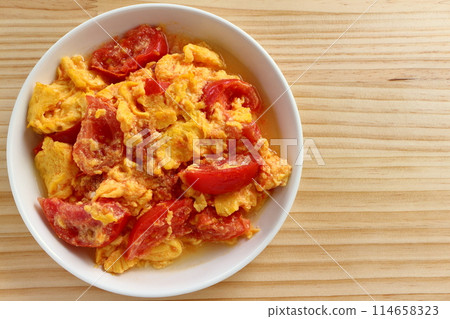 Fried eggs with tomatoes on table background Fried eggs with tomatoes on table background 114658323