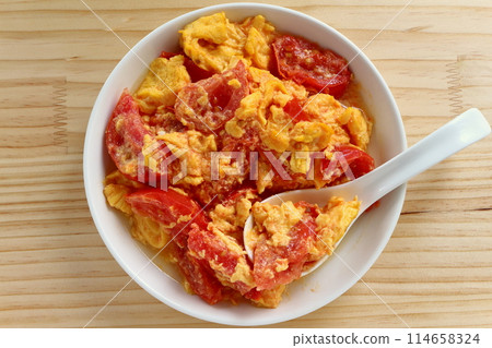 Fried eggs with tomatoes on table background 114658324