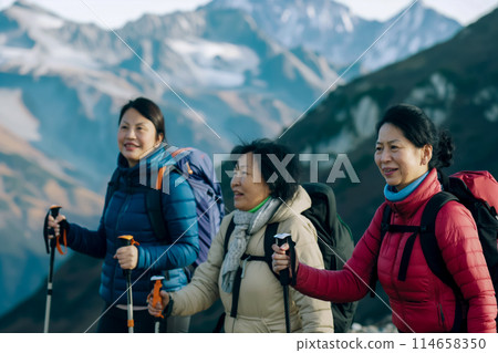 Portrait of a group of adult women enjoying a walk in a mountain hike, holding Nordic walking poles, active senior lifestyle 114658350