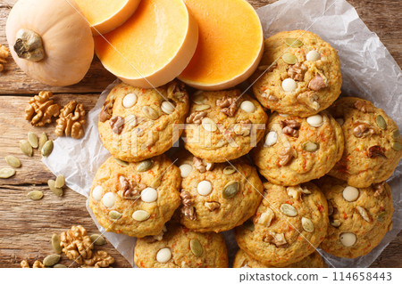 Thanksgiving pumpkin cookies with white chocolate, walnuts and seeds close-up on parchment. Horizontal top view 114658443