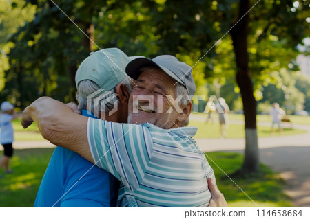 close-up of mature men hugging, active life and health in retirement, meeting and hugging two old friends meeting in the park before playing sports close-up of mature men hugging, active life and health in retirement, meeting and hugging two old friends meeting in the park before playing sports 114658684