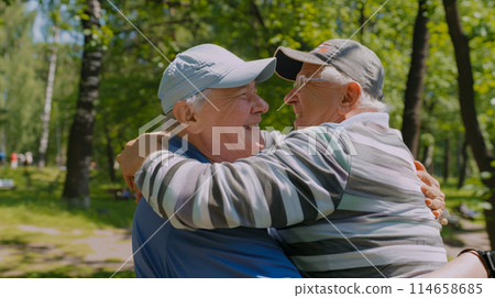 Meeting and hugging of two old friends meeting in the park before playing sports, close-up of mature men hugging, active life and health in retirement Meeting and hugging of two old friends meeting in the park before playing sports, close-up of mature men hugging, active life and health in retirement 114658685