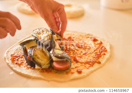 Italian traditional dish calzone, chef's hands adding ingredients to pizza dough Italian traditional dish calzone, chef's hands adding ingredients to pizza dough 114658967