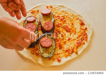 Cooking calzone, chef adds salami to a great dish, delicious traditional Italian dessert, gastronomic trip to Italy, blurred background Cooking calzone, chef adds salami to a great dish, delicious traditional Italian dessert, gastronomic trip to Italy, blurred background 114658968