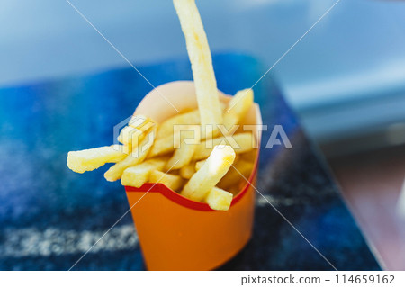 Crispy and Delicious Golden French Fries Served in a Paper Cup on a Wooden Table Crispy and Delicious Golden French Fries Served in a Paper Cup on a Wooden Table 114659162
