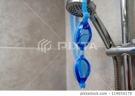 Goggles for swimming hanging on a metal hook in the shower room Goggles for swimming hanging on a metal hook in the shower room 114659179