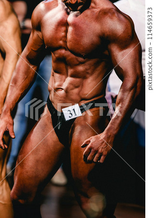 man bodybuilder athlete show front pose in bodybuilding competition 114659373
