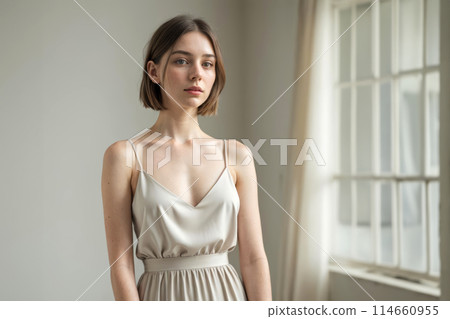 Serene Woman Posing in a Softly Lit Room Near a Window pastel tone and mood of the quiet luxury look. 114660955