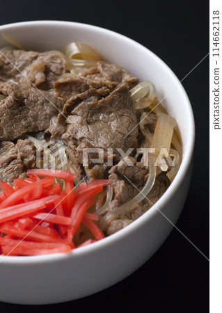 Photo of beef bowl topped with pickled ginger on a black background Photo of beef bowl topped with pickled ginger on a black background 114662118