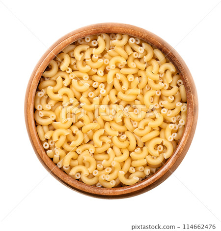 Gramigna, minute pasta, in a wooden bowl. Also called pastina, meaning little or small pasta. Uncooked, tiny elbow shaped tubes, made with durum, used as ingredient of soup, desserts, and infant food. 114662476