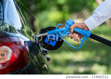 Man holds a hydrogen fueling nozzle. Refueling car with hydrogen fuel. Concept Man holds a hydrogen fueling nozzle. Refueling car with hydrogen fuel. Concept 114662512