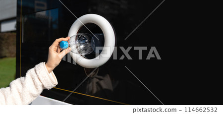 Woman uses a self service machine to receive used plastic bottles and cans on a city street.. Woman uses a self service machine to receive used plastic bottles and cans on a city street.. 114662532