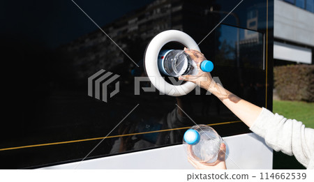 Woman uses a self service machine to receive used plastic bottles and cans on a city street.. 114662539