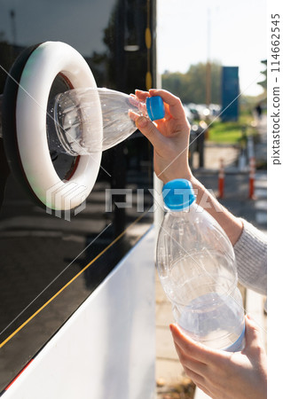 Woman uses a self service machine to receive used plastic bottles and cans on a city street.. 114662545