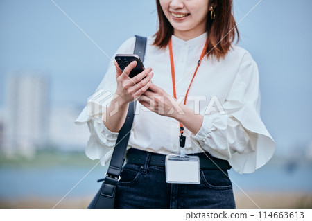 一位年輕女子邊走邊使用智慧型手機 114663613