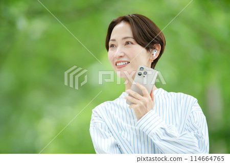 鮮綠色，戴著耳機、拿著智慧型手機的女人 114664765
