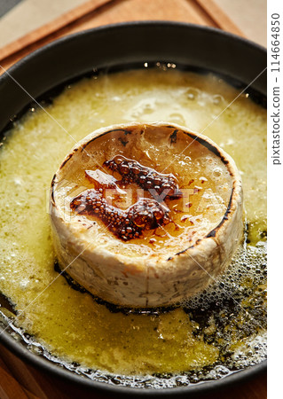 Browned torched Camembert cheese in black iron skillet 114664850