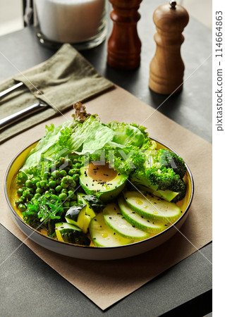 Plate of green vegan salad with fresh veggies and peanut dressing 114664863