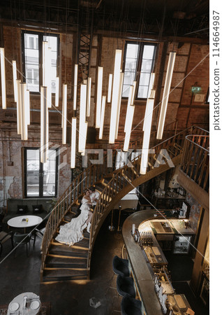A young couple in wedding looks posing in a stylish loft bar. 114664987