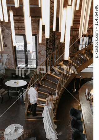 A young couple in wedding looks posing in a stylish loft bar. A young couple in wedding looks posing in a stylish loft bar. 114664996