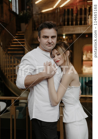 A young couple in wedding looks posing in a stylish loft bar. A young couple in wedding looks posing in a stylish loft bar. 114665168
