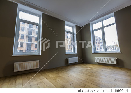 New renovated room interior with big windows, heating radiators and wooden parquet floor New renovated room interior with big windows, heating radiators and wooden parquet floor 114666644