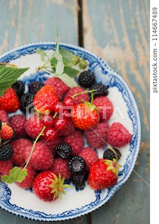 Raspberries, strawberry and wild blackberries on a vintage plate Raspberries, strawberry and wild blackberries on a vintage plate 114667489