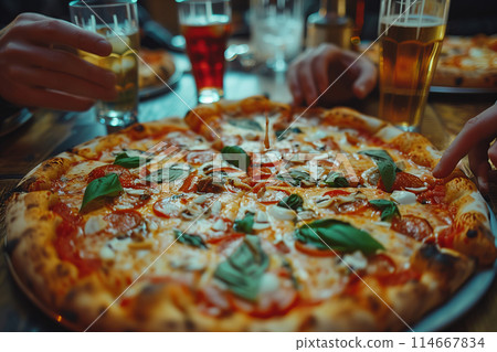 Close-up of friends sharing pizza at a table in a restaurant. 114667834