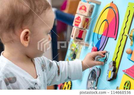 The kid is concentratedly spinning the wheel on the game board The kid is concentratedly spinning the wheel on the game board 114668536