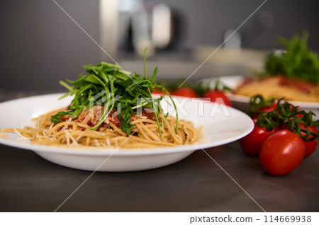 Food background with classic Italian cuisine dish. Pasta spaghetti with tomatoes, arugula leaves and parmesan cheese. Copy advertising space. Classic Italian cuisine dish. 114669938