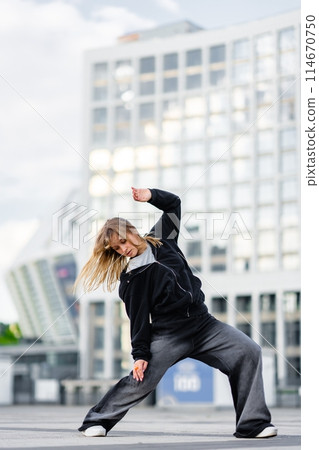 A young woman wears oversized clothes and dances hip-hop. A young woman wears oversized clothes and dances hip-hop. 114670750