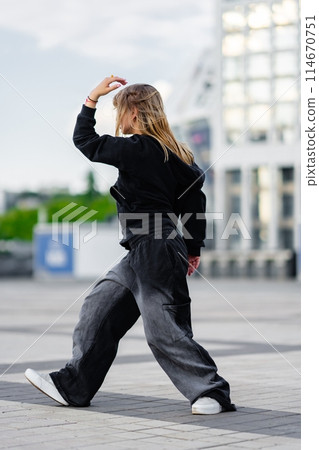 A young woman wears oversized clothes and dances hip-hop. A young woman wears oversized clothes and dances hip-hop. 114670751