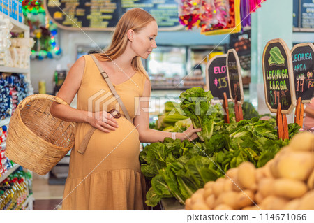 A pregnant woman is at a fruit stand in a grocery store Pregnant woman buying organic vegetables and fruits at Mexican style farmers market 114671066
