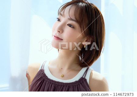 A woman relaxing in a room through lace curtains 114672973