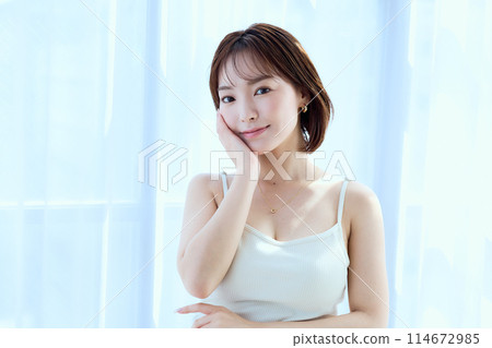 A woman relaxing in a room through lace curtains A woman relaxing in a room through lace curtains 114672985