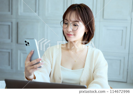 一位女士在家一邊工作一邊看智慧型手機 114672996