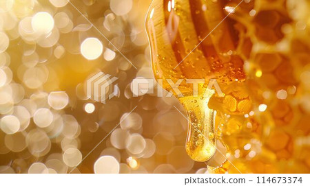 Honey dripping from the wooden honey dropper over thick golden honeycomb on a blurred background. A close up view of the natural organic sweet product. 114673374