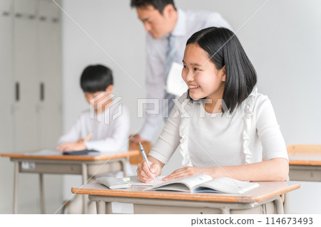 微笑的高年級小學生(補習班/暑期班)和男老師在學校課堂上享受學習樂趣 微笑的高年級小學生(補習班/暑期班)和男老師在學校課堂上享受學習樂趣 114673493