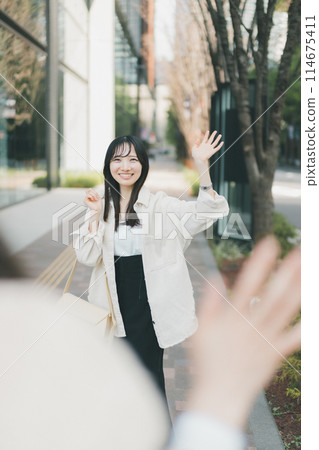 A woman waving to her meeting partner at a meeting place 114675411