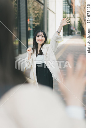 A woman waving to her meeting partner at a meeting place 114675416
