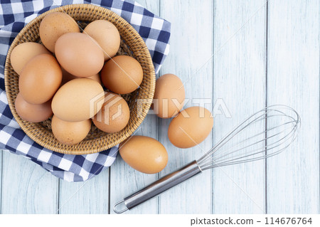 Top view of organic chicken eggs in wooden basket on blue wooden floor. 114676764