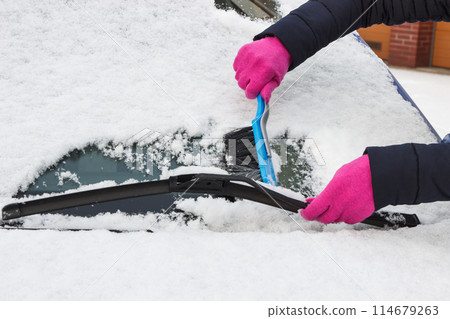 Hand of woman using brush and remove snow from car and windscreen 114679263