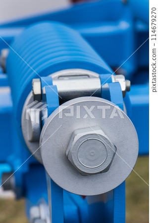 Blue hard spring made of steel. Part of big industrial or agricultural machine 114679270