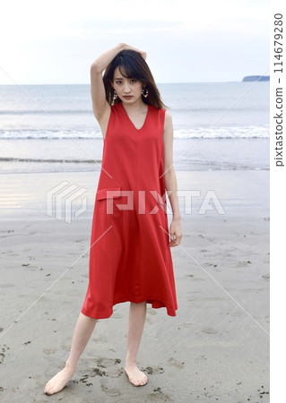 A young woman in a red dress posing on the beach A young woman in a red dress posing on the beach 114679280