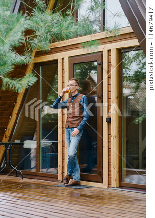 a man goes out onto the wet terrace with a glass of whiskey and enjoys the fresh air after the rain a man goes out onto the wet terrace with a glass of whiskey and enjoys the fresh air after the rain 114679417