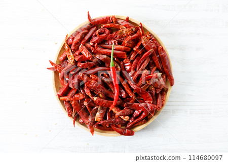 Dried red chilies on wooden tray. 114680097